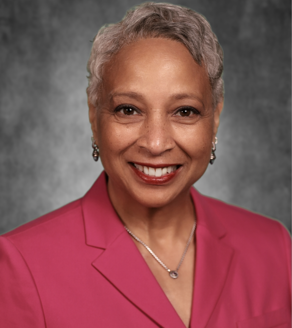 Woman wearing a pink jacket, smiling for a headshot.