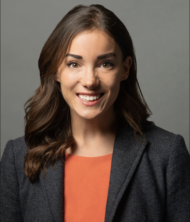 White woman posing for a headshot in an orange shirt.