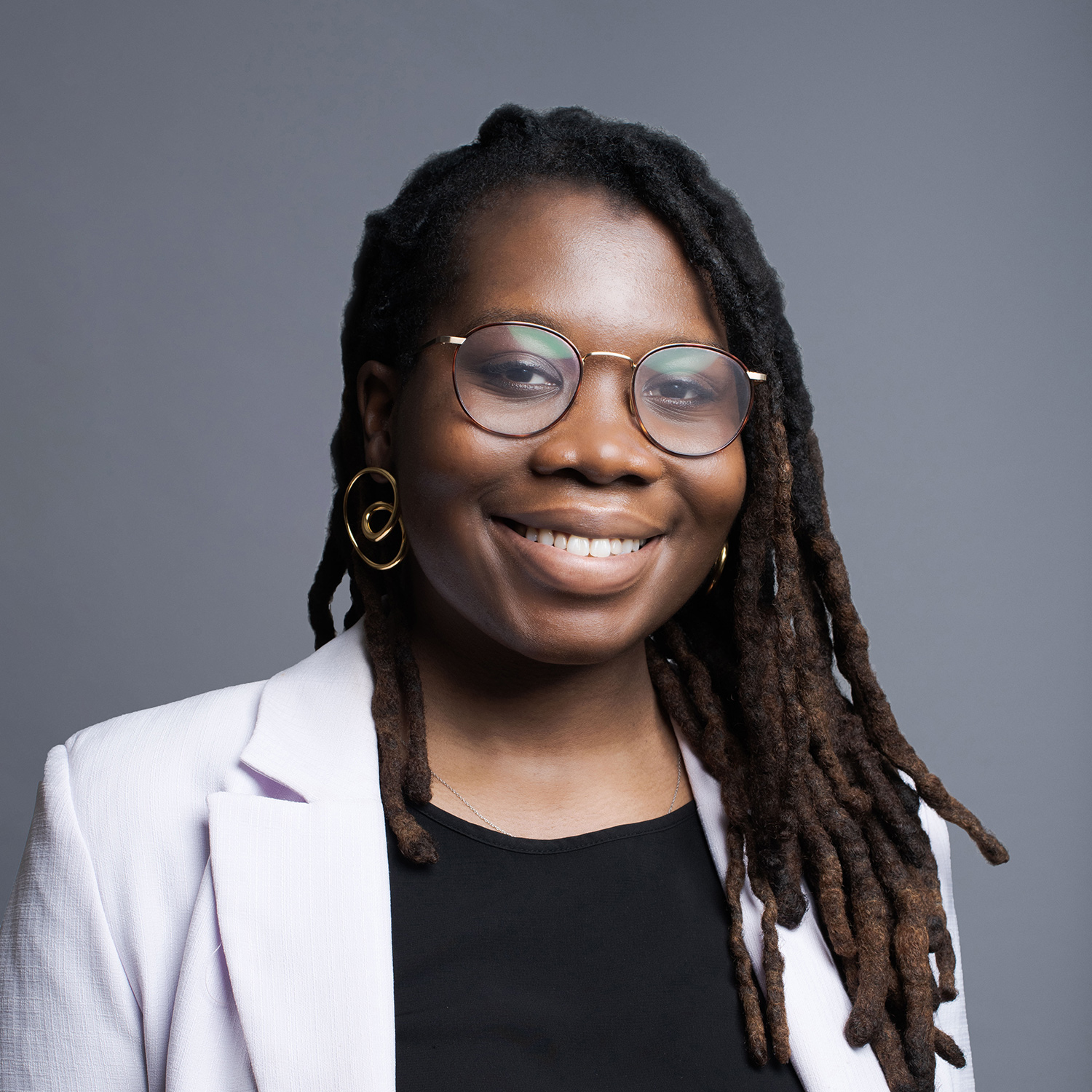 Black woman posing for a headshot against a gray background.