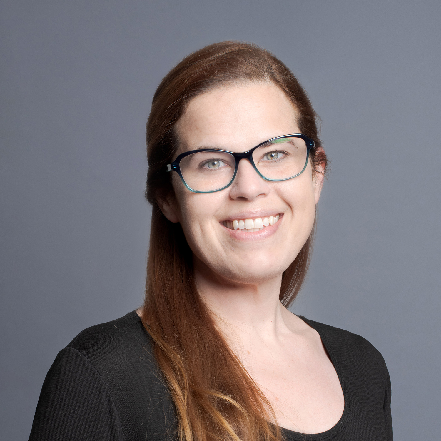 White woman posing for a headshot against a gray background.