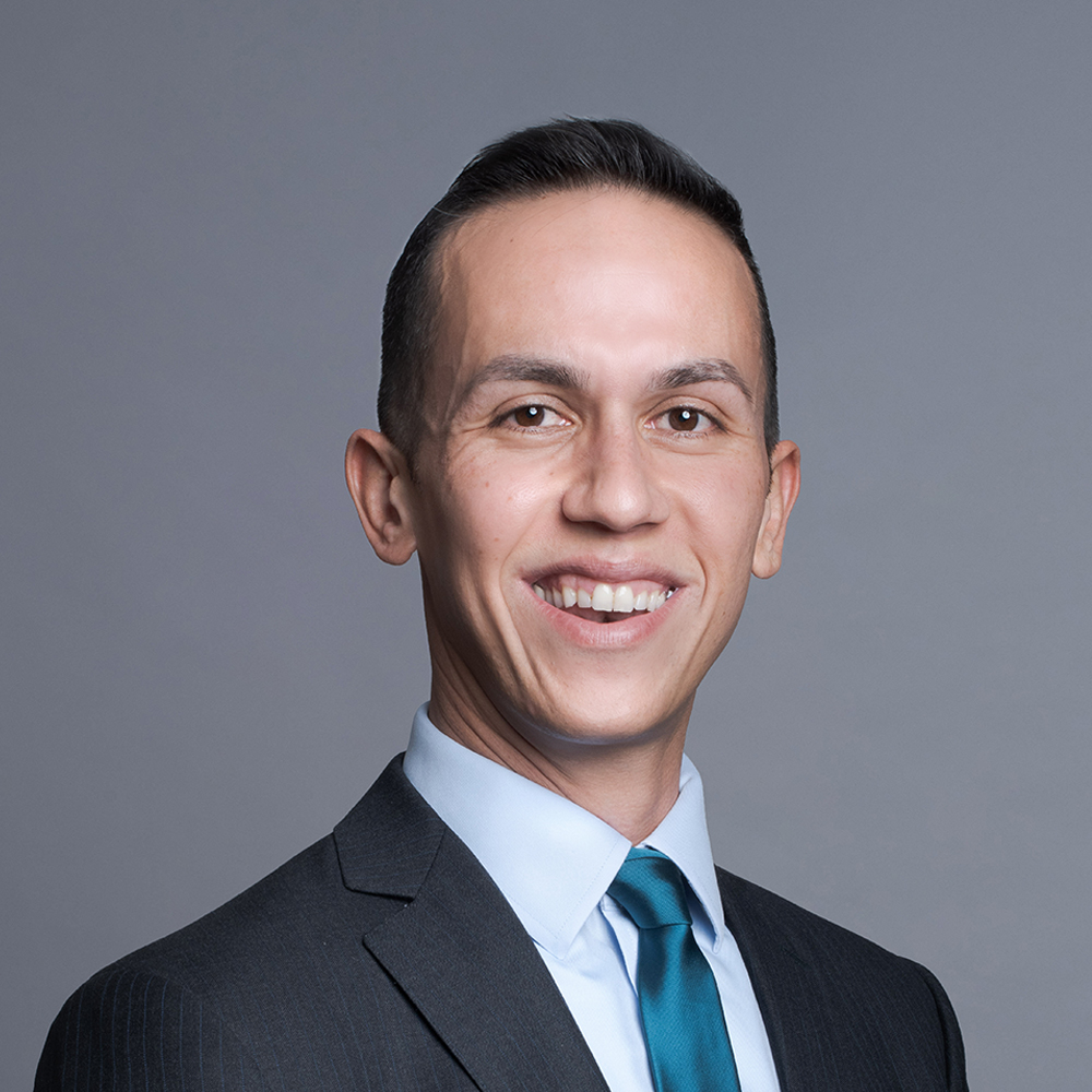 White man posing for a headshot against a gray background.