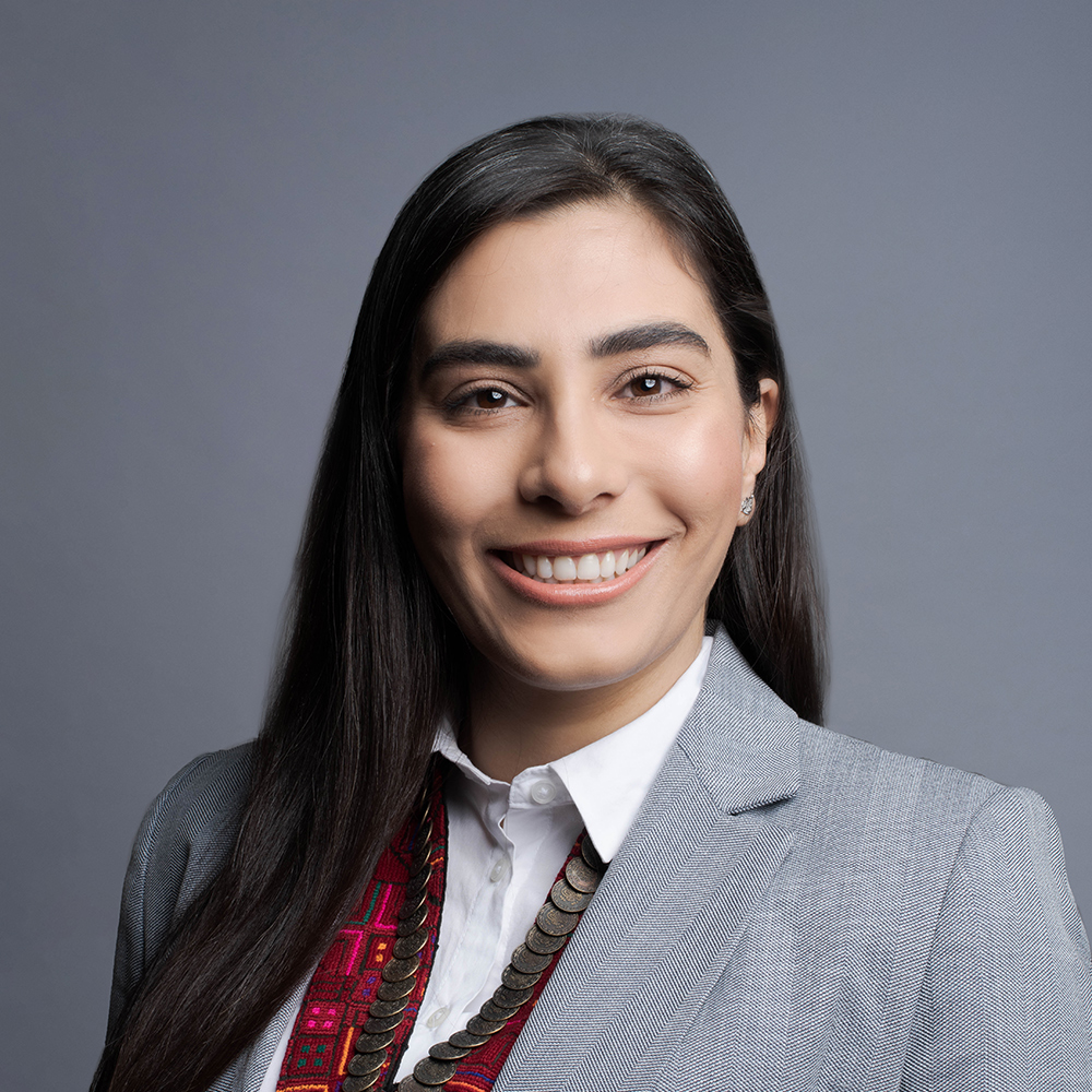 Woman posing for a headshot against a gray background.