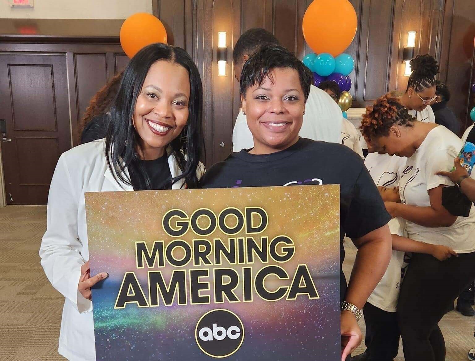 Two women holding a Good Morning America sign