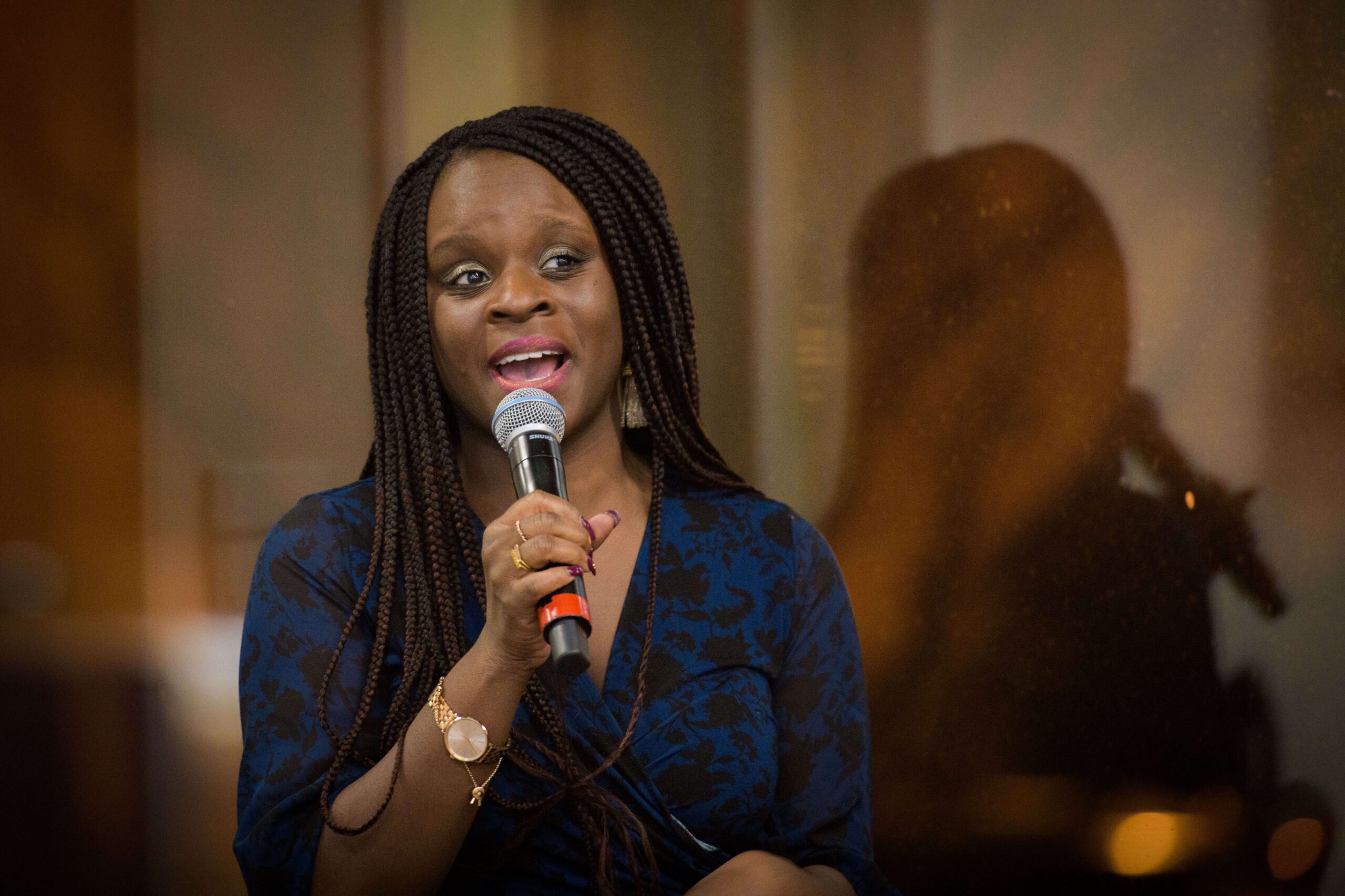 Nkem Osian speaking into a microphone at a reception.