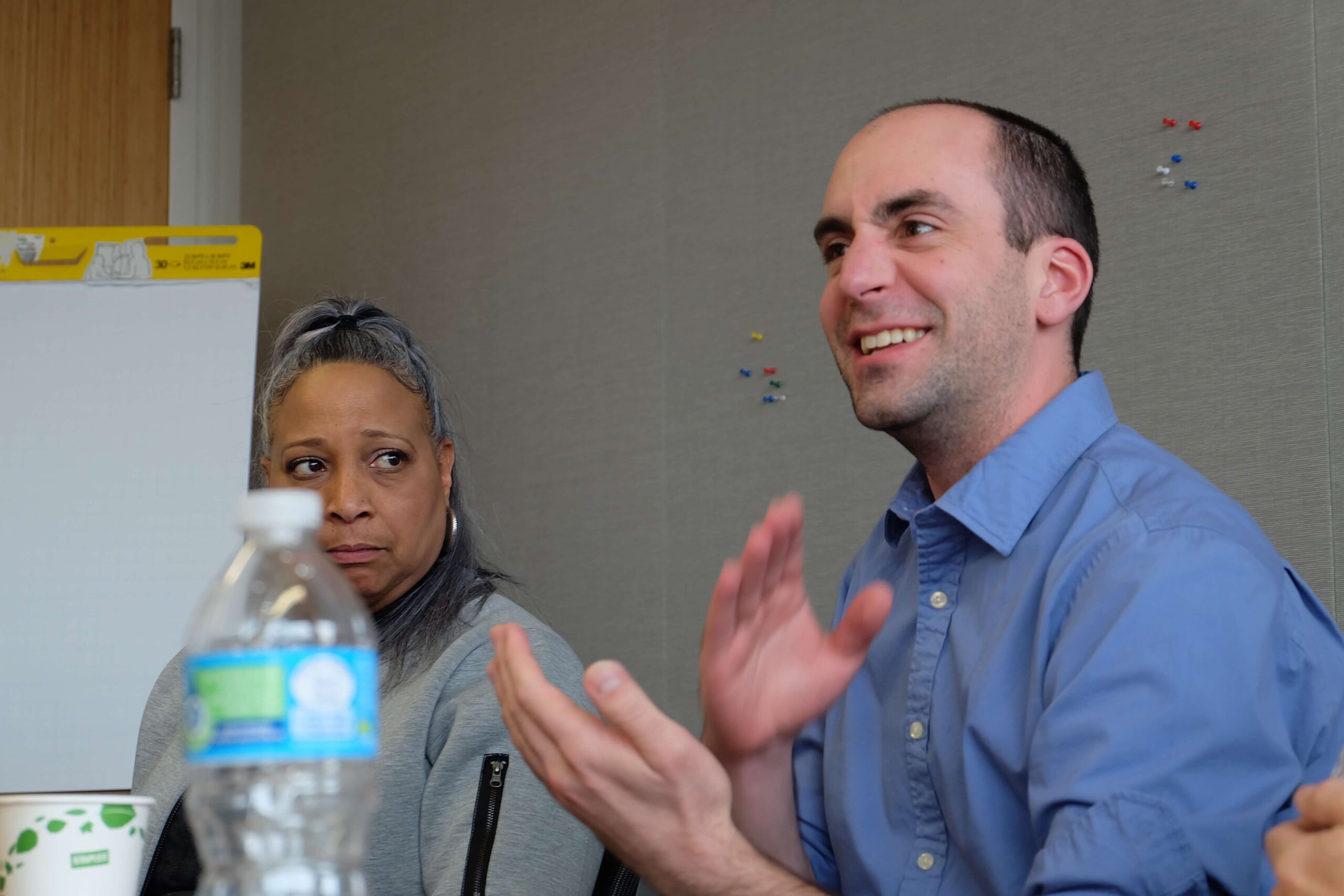 Man in a blue shirt speaking and gesturing with his hands.