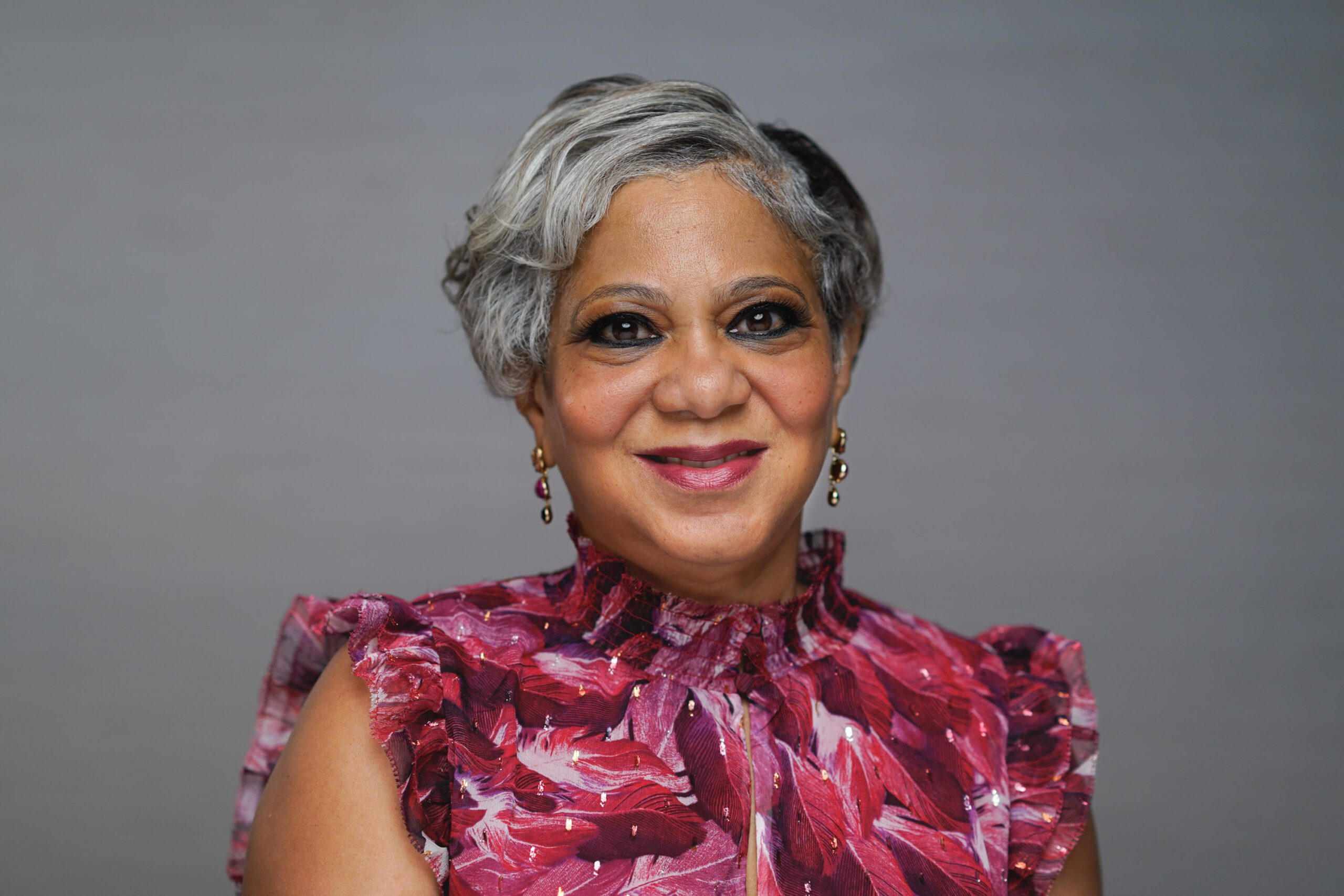 woman wearing a pink shirt against a gray background