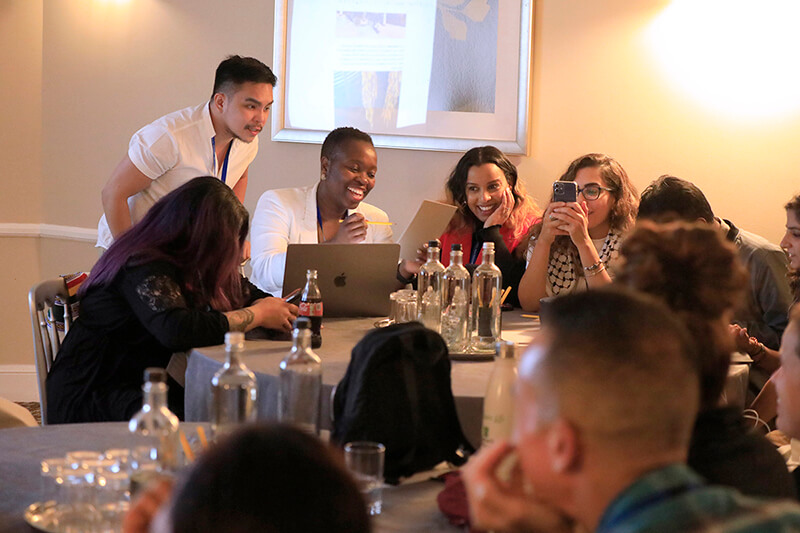 Group of people laughing and smiling in front of a computer.