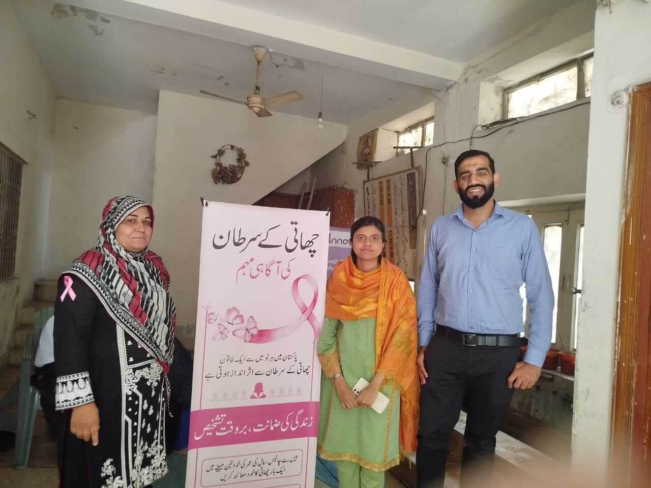 Three people standing next to a pink roll up banner.