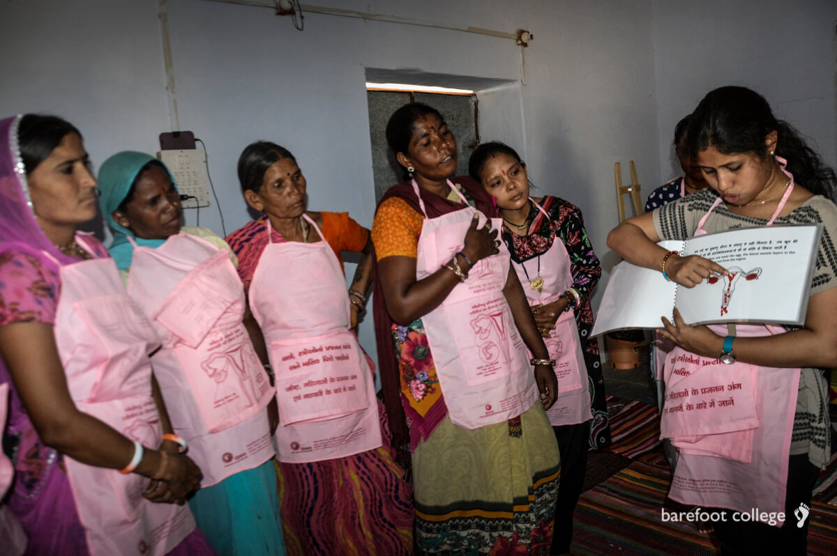 Woman holding up a book and explaining something to a group of women.