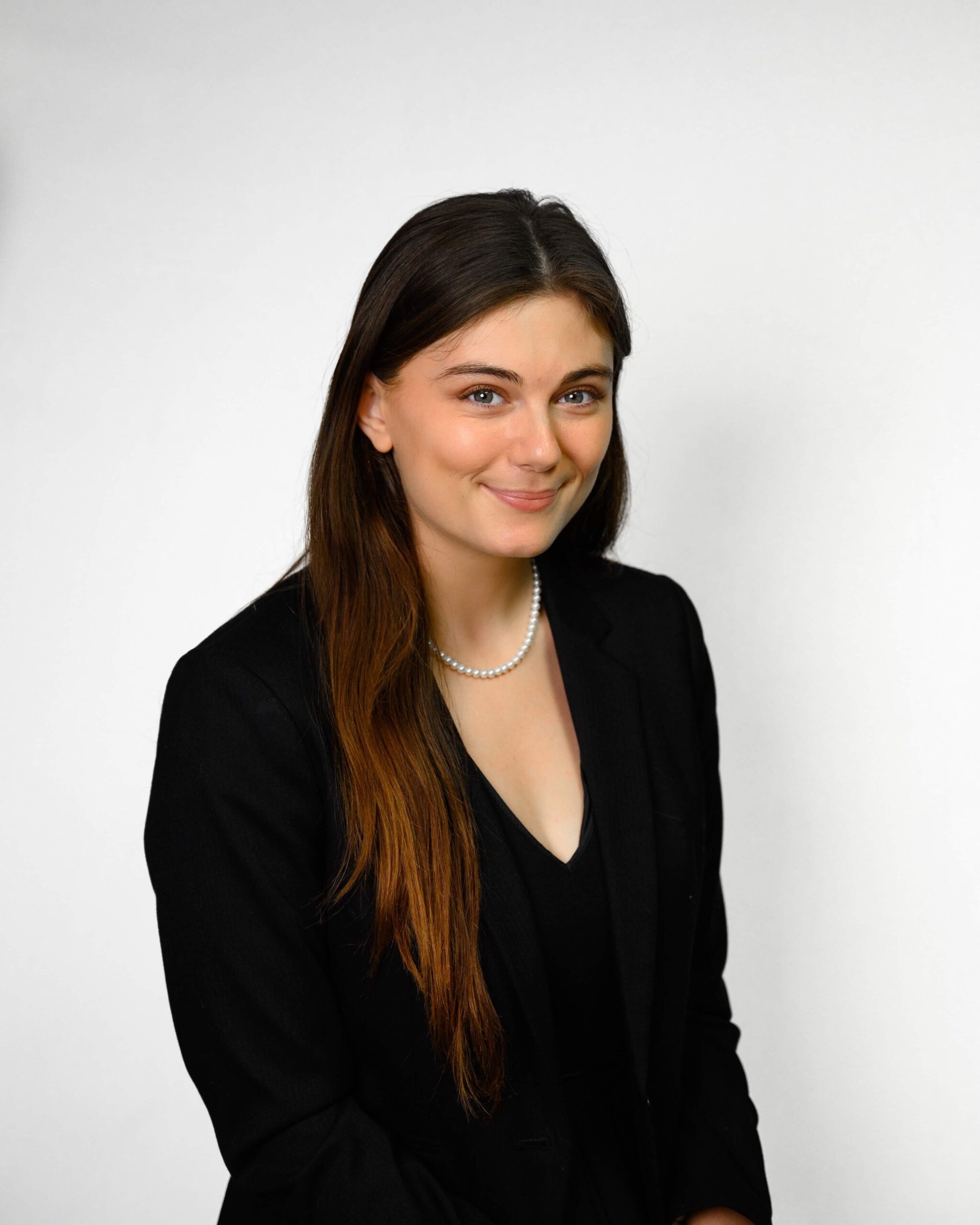 Woman posing for a headshot against a white and gray background