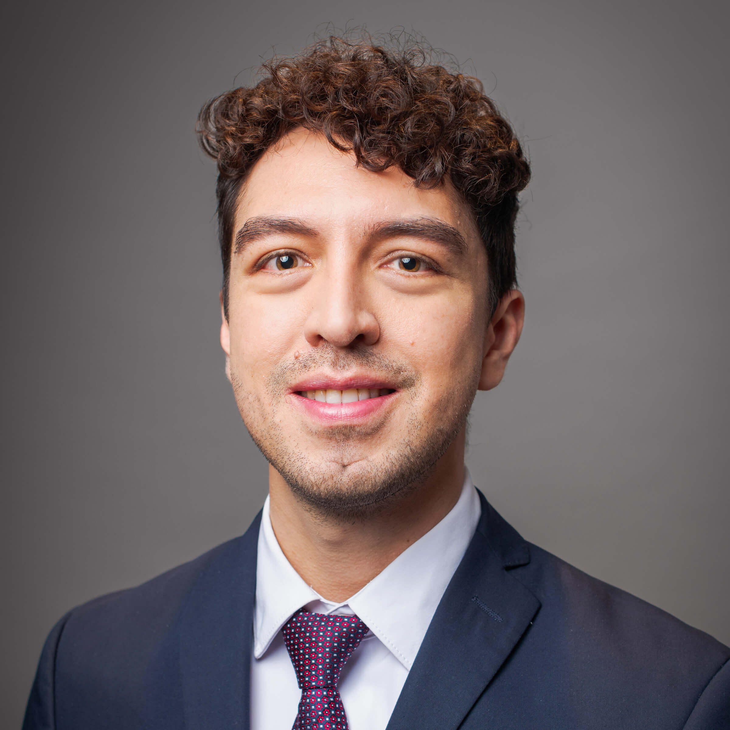 Man posing for a headshot against a gray background.