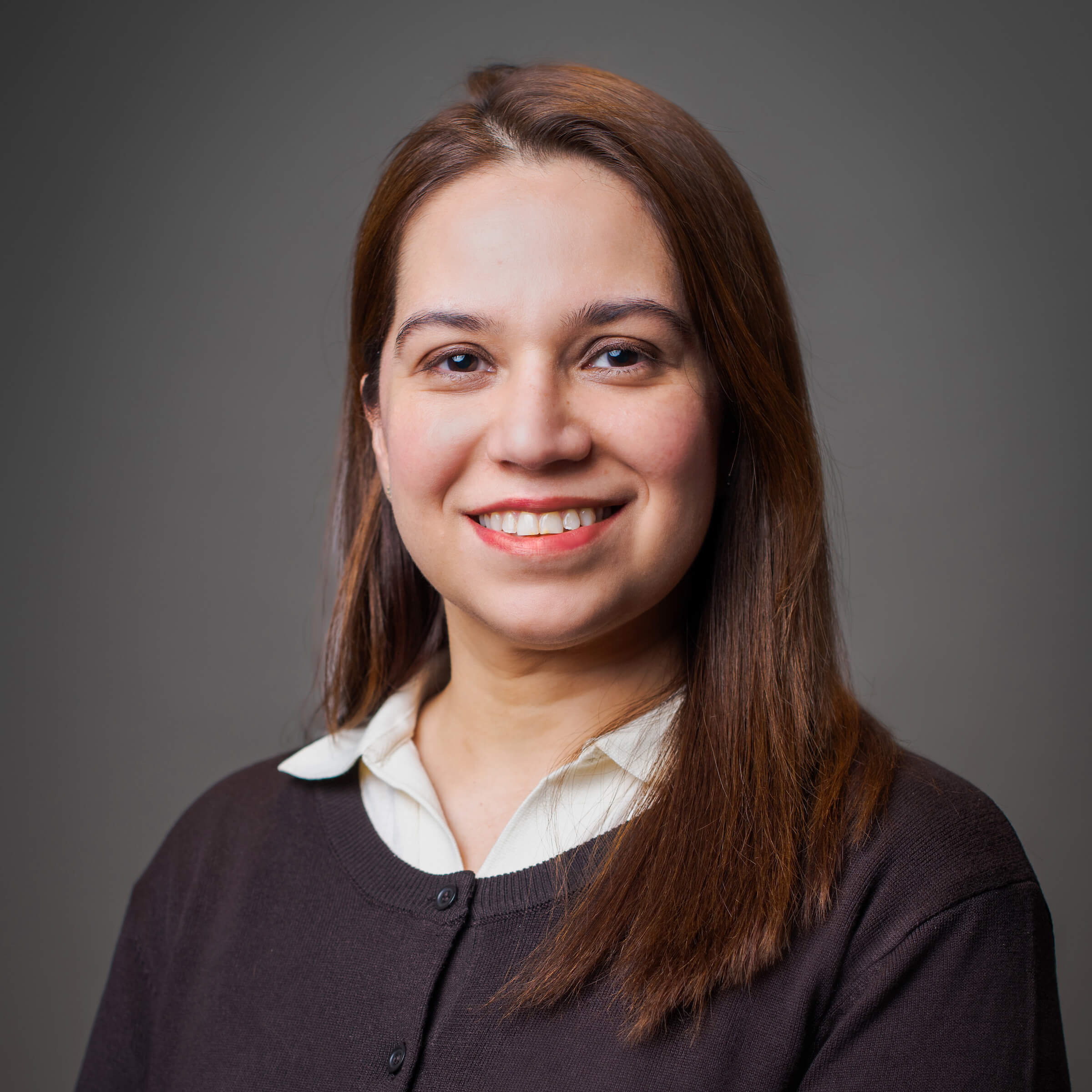 Woman posing for a headshot against a gray background.