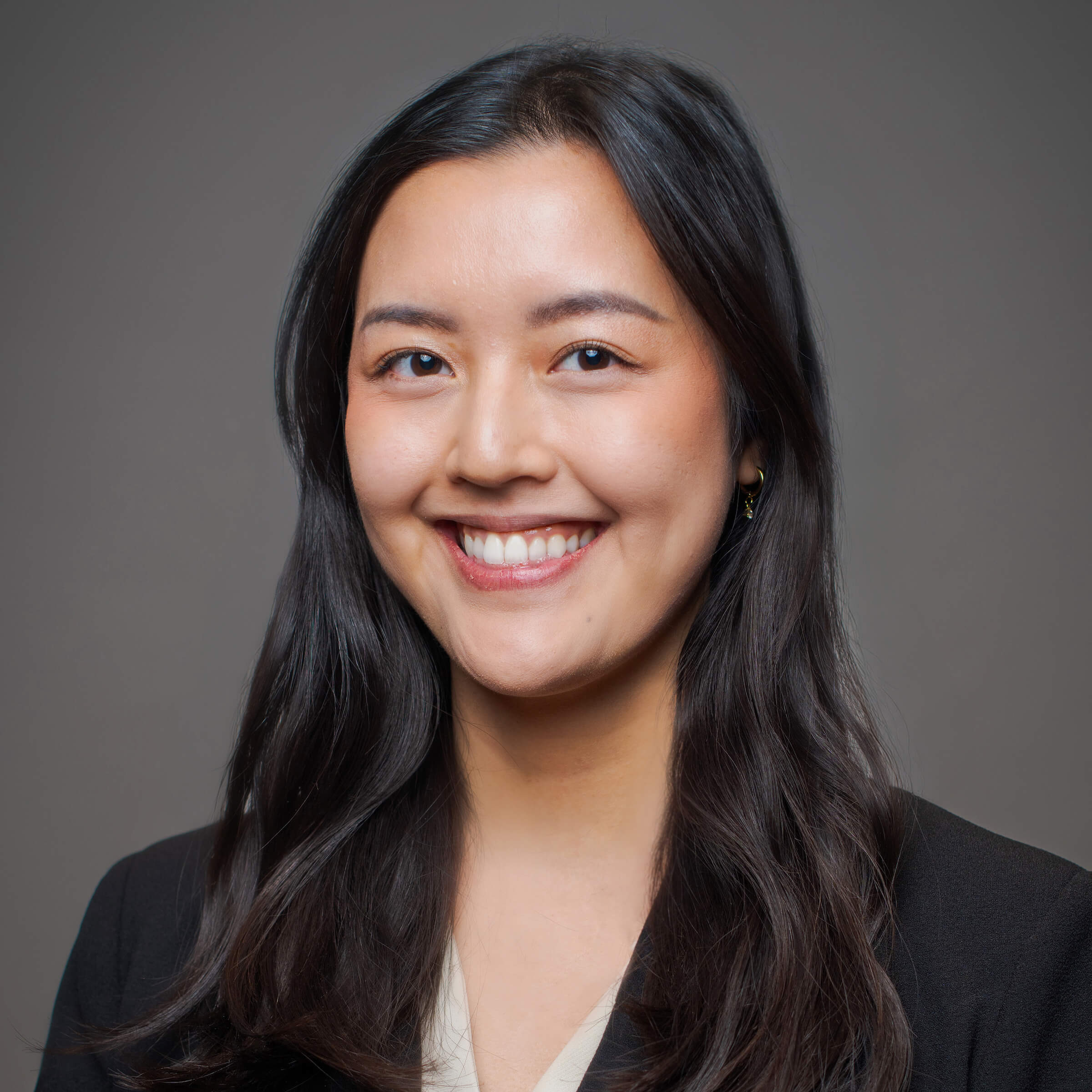 Woman posing for a headshot against a gray background.