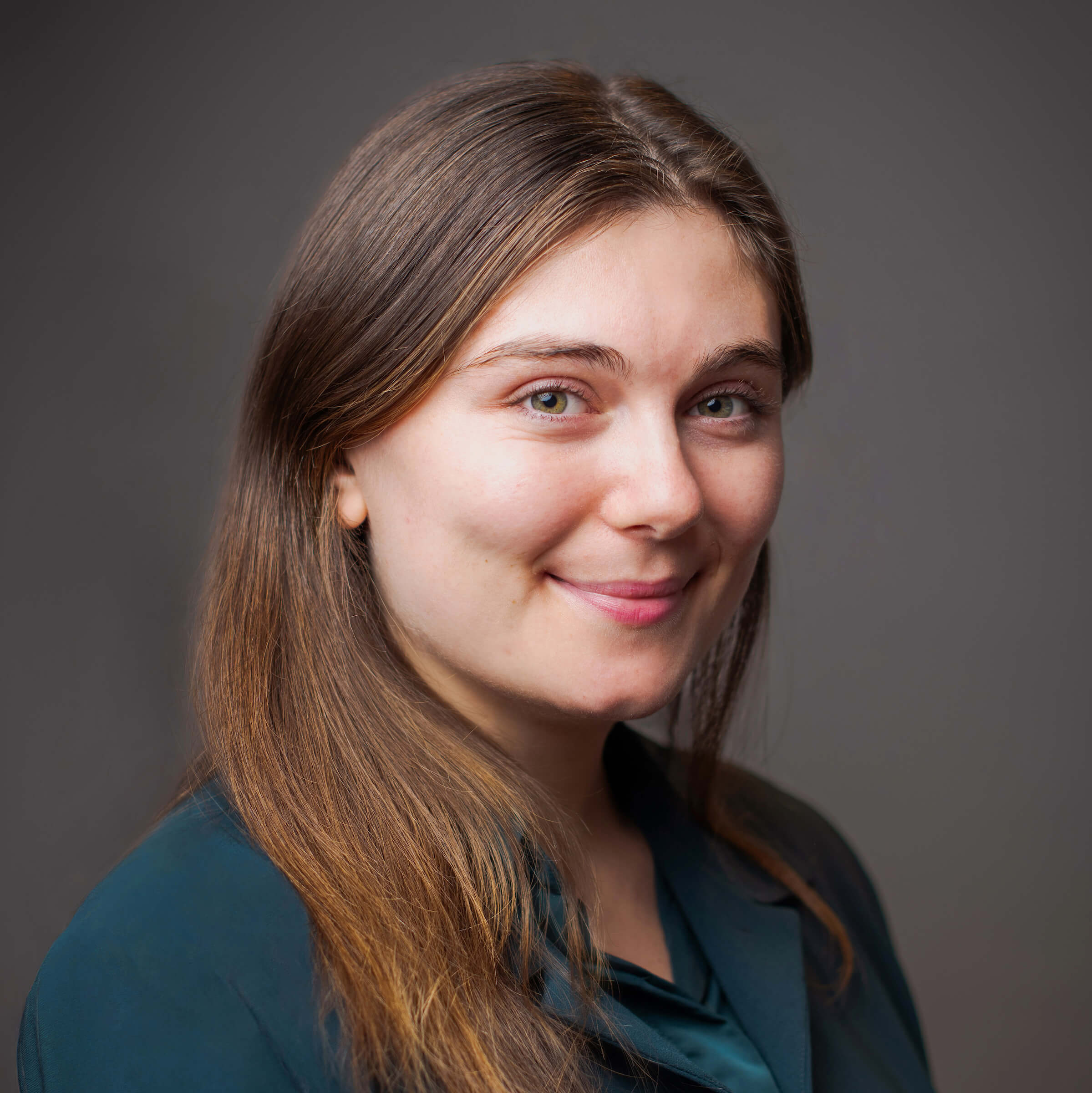 White woman posing for a headshot on a gray background.