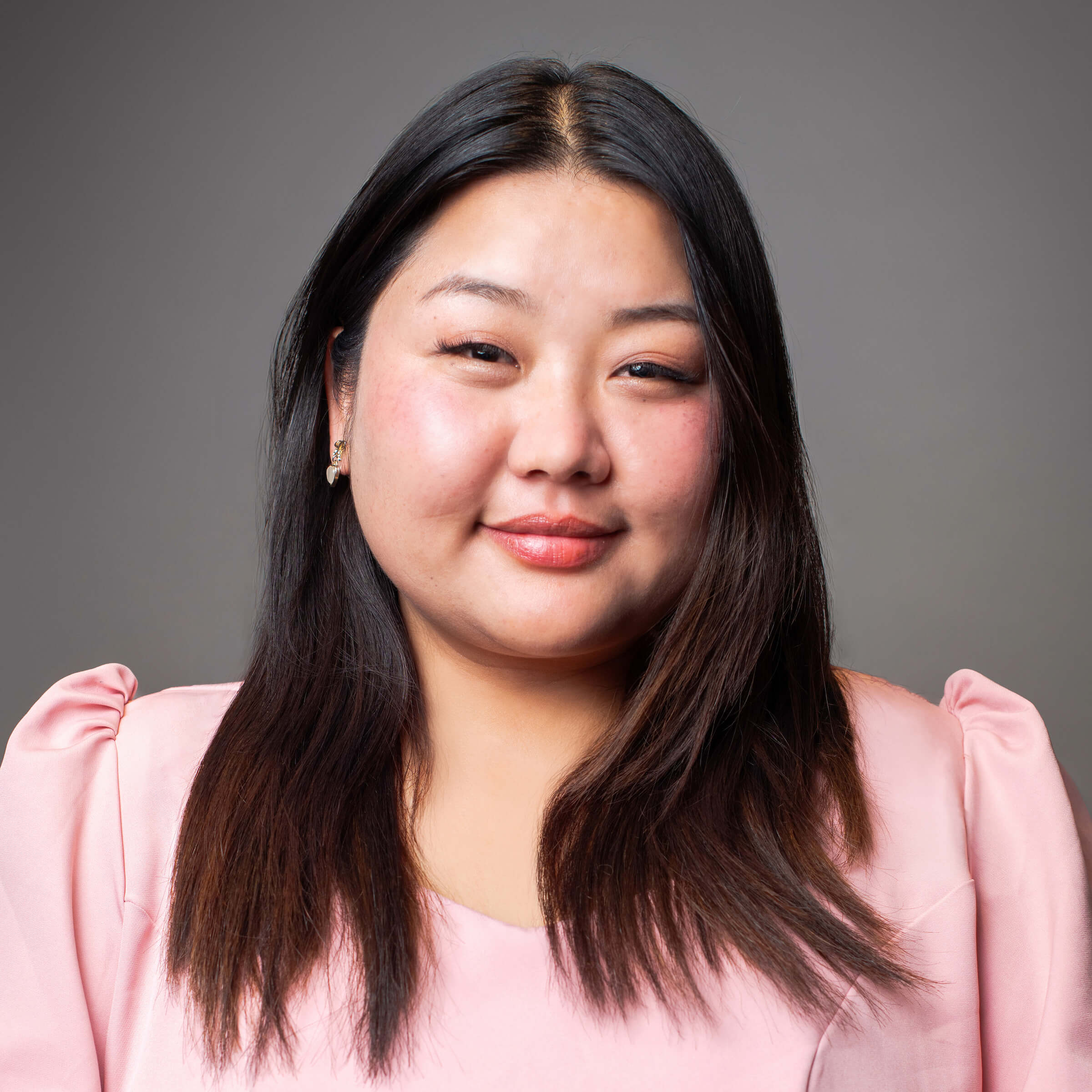 Woman posing for a headshot against a gray background.