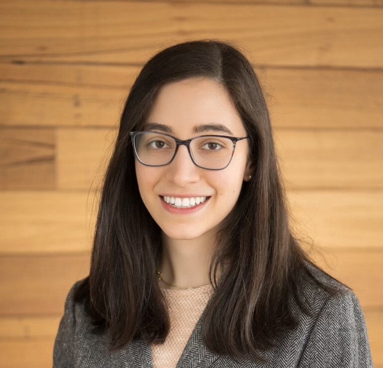 Woman posing for a headshot against a wood backdrop.