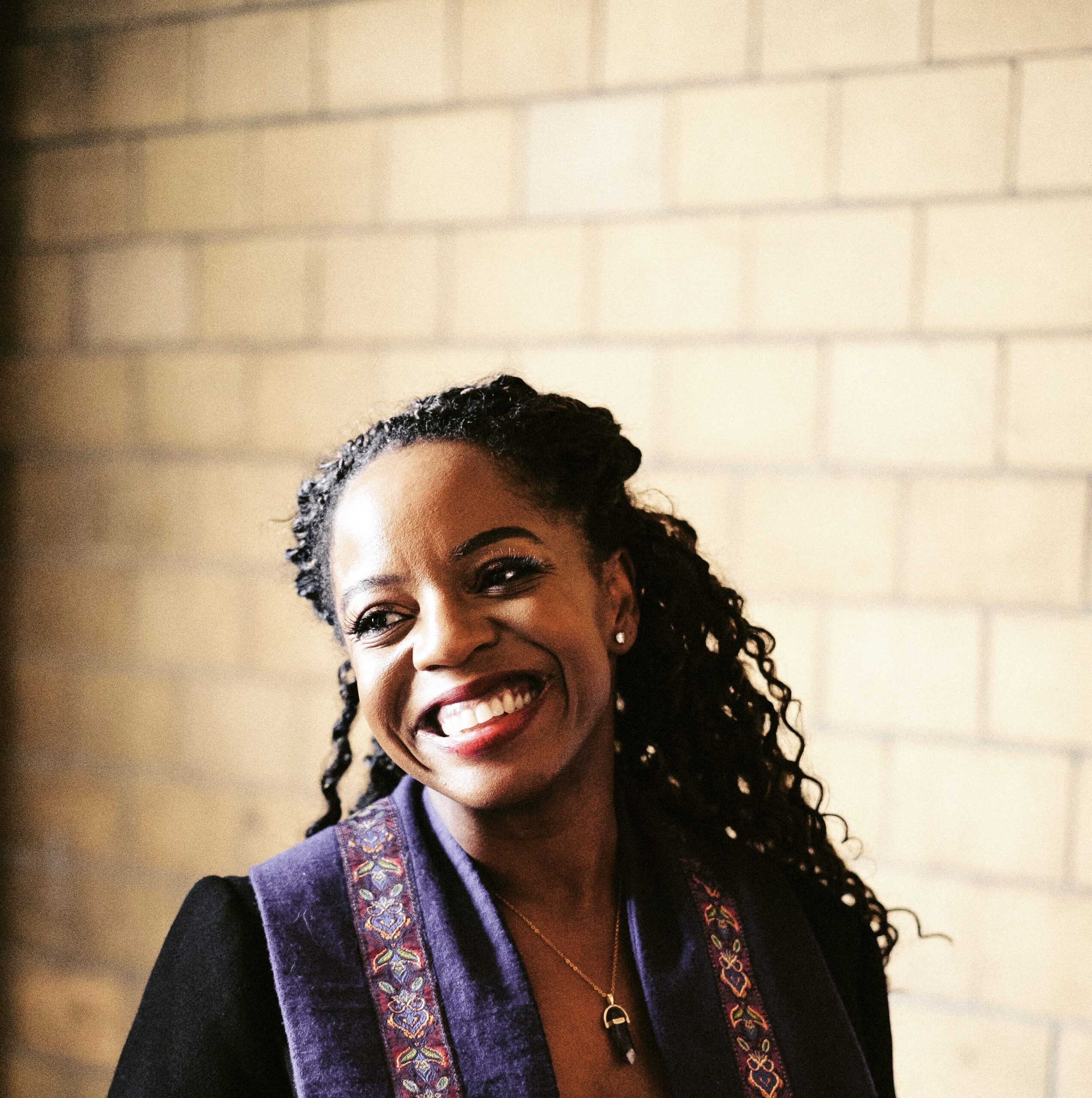 Woman posing for a headshot with brick background.