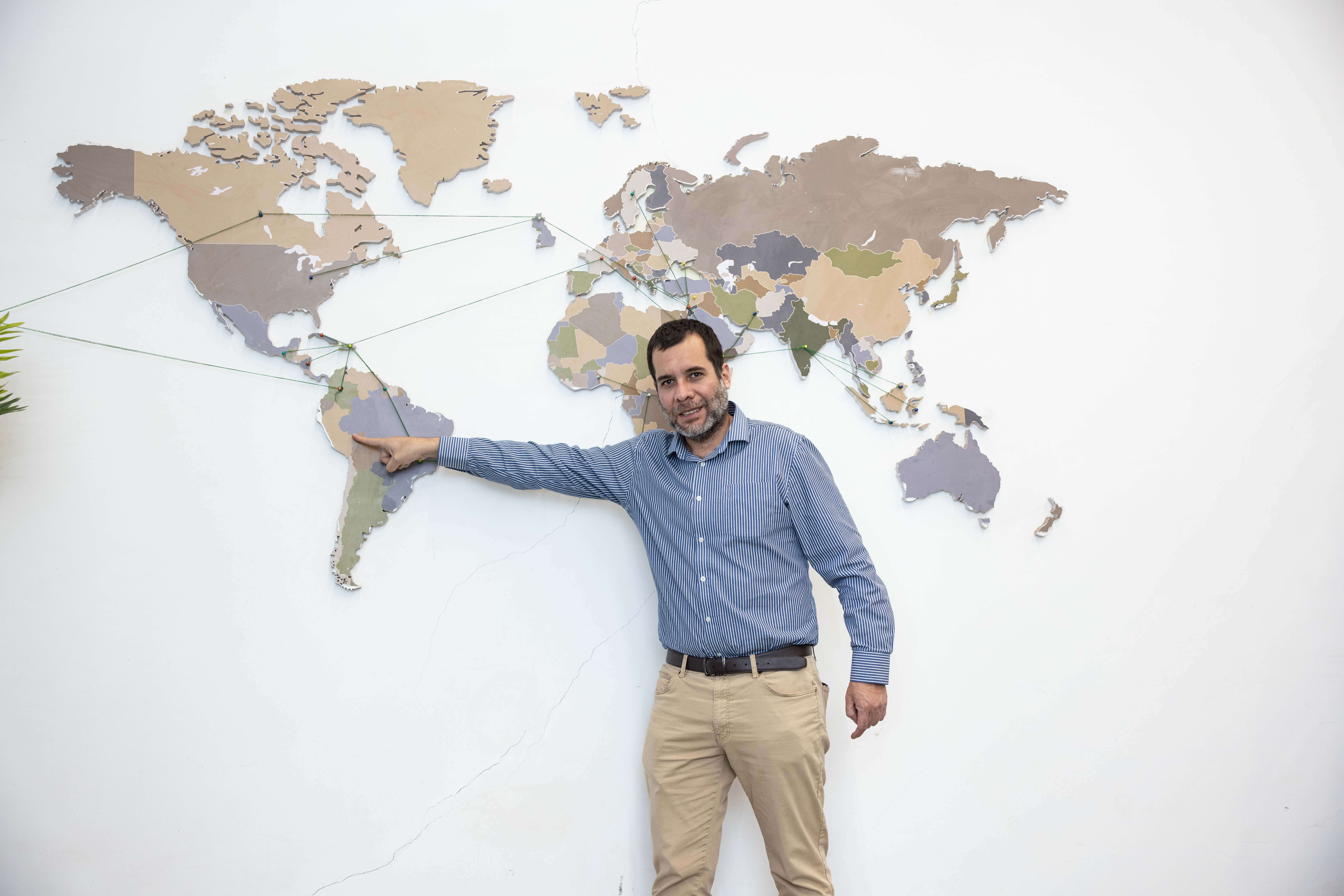 A man pointing at a large wall world map.