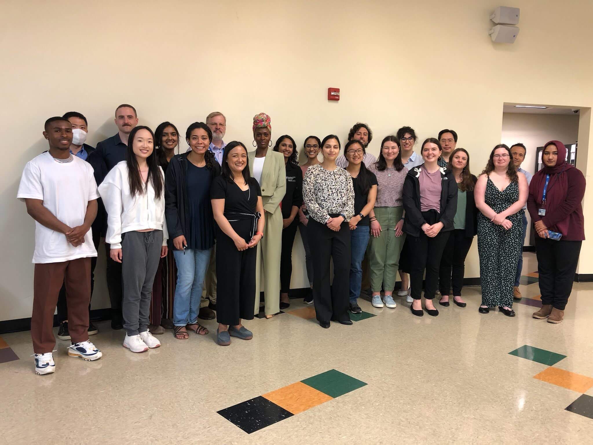 A diverse group of young adults and professionals posing for a group photo indoors.