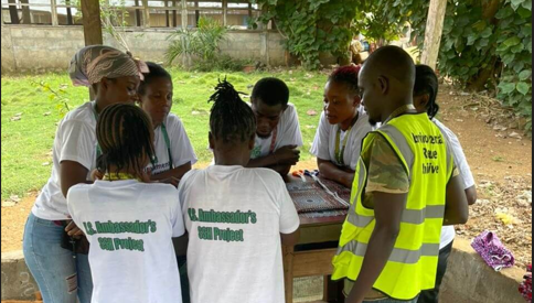 A group of people outdoors, standing around a tall wooden table.